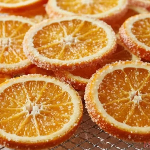 beautiful pile of translucent candied orange slices drying on a wire rack, shimmering with sugar crystals
