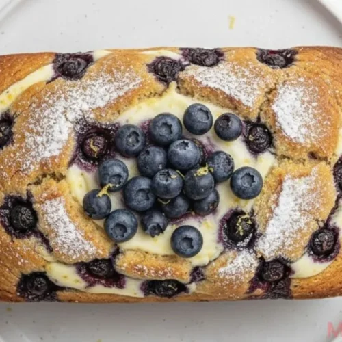 Slices of moist Blueberry Cream Cheese Bread on a wooden board with fresh berries