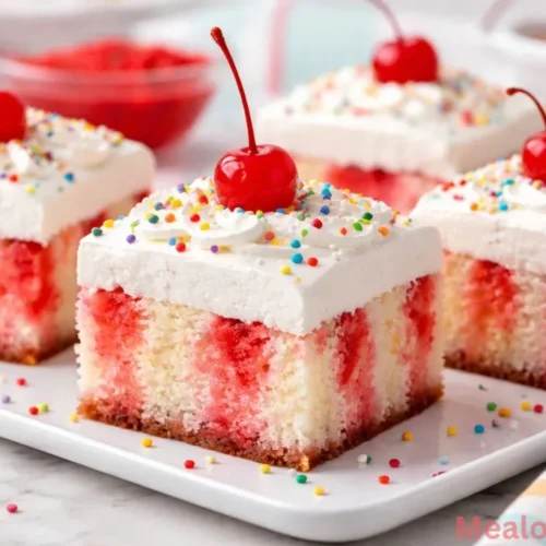 Sliced strawberry jello poke cake with whipped topping on a white plate.
