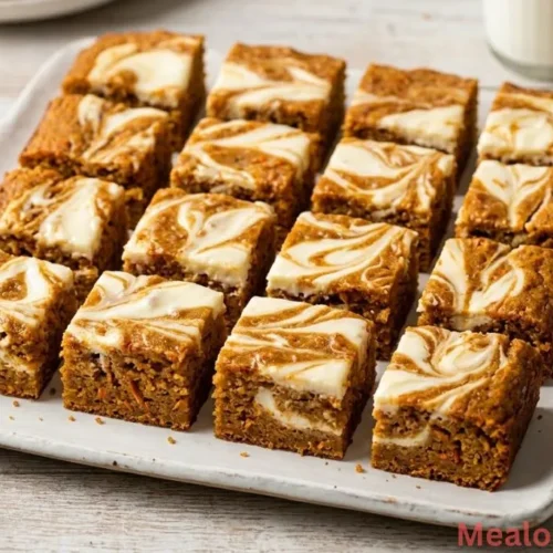 view of sliced carrot cake bars with cream cheese marbling on a white platter